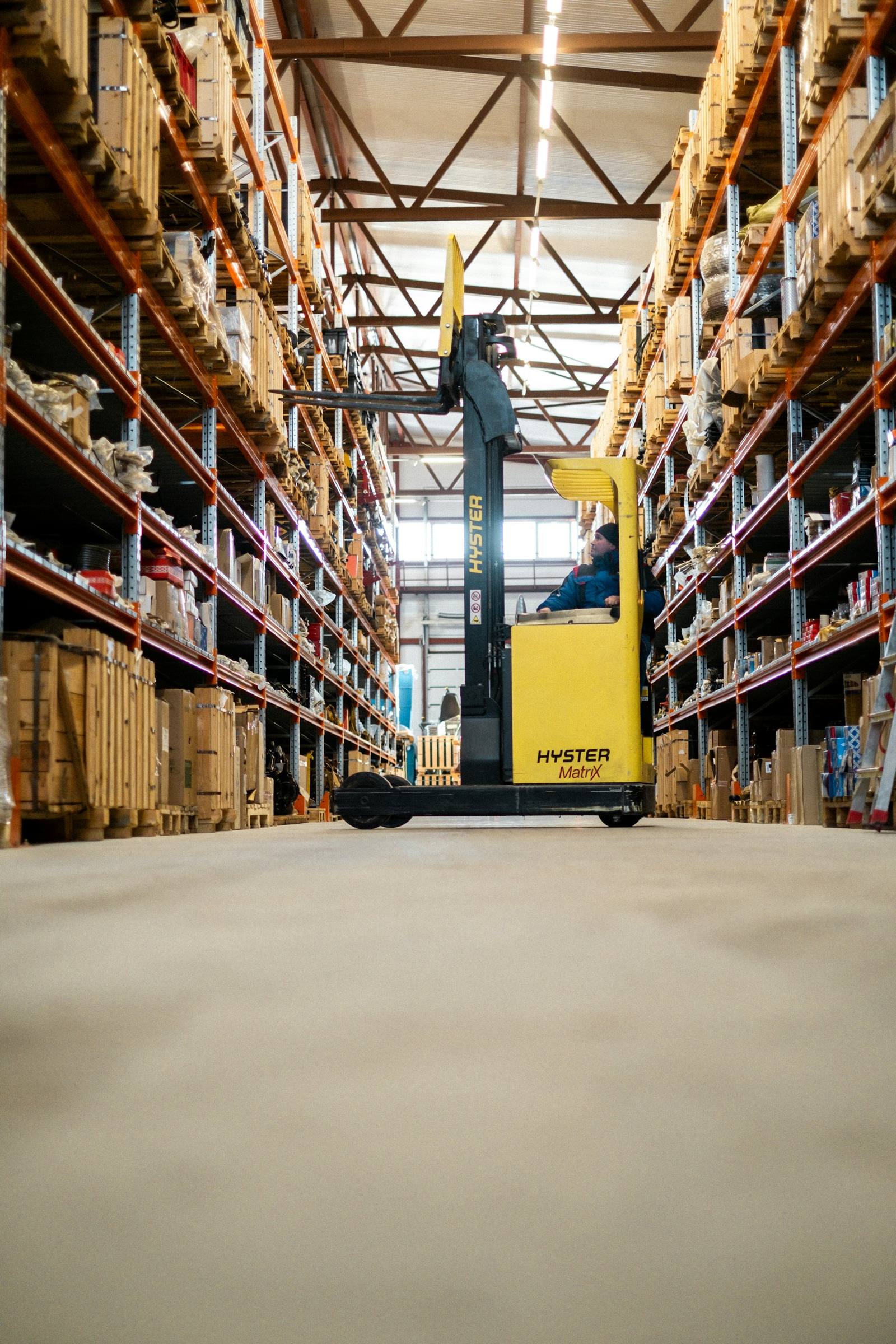 Modern distribution warehouse aisle with a reach truck between stocked racks